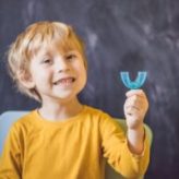 Three-year old boy shows myofunctional trainer. Helps equalize the growing teeth and correct bite, develop mouth breathing habit. Corrects the position of the tongue.